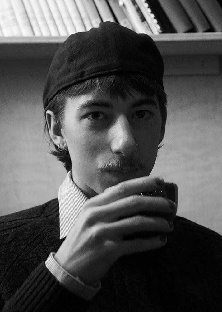 Portrait eines adrett gekleidet, Kaffee trinkenden, jungen Mannes in Schwarz und Weiß.