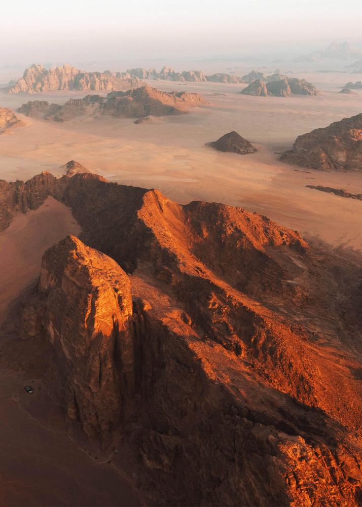 Eine Wüstenlandschaft mit sandigen Dünen und felsigen Hügeln, die sich bis zum Horizont erstrecken.
