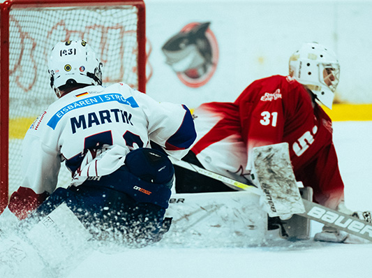 Zwei Eishockey Spieler, die sich kurz vor dem Tor jeweils auf den Knien begegnen.