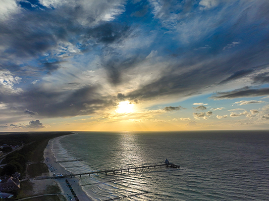 Auf diesem Bild sieht man einen Sonnenuntergang über dem Wasser in Zingst.