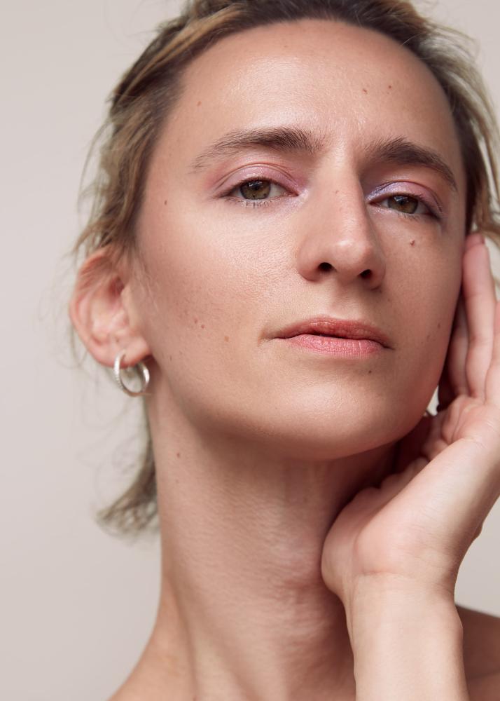 Portrait einer Person, die sich mit der Hand über die Wange streicht.