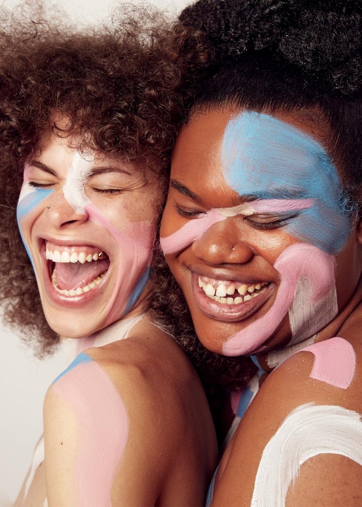 Portrait zweier Personen mit kunstvoller Gesichtsbemalung die stark lachen.