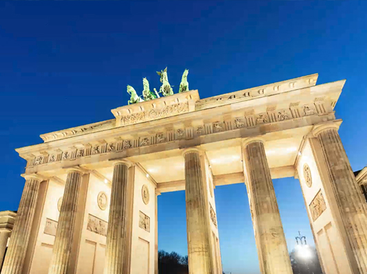 Das Brandenburger Tor in Berlin bei Nacht, beleuchtet und mit einer Statue auf der Spitze.