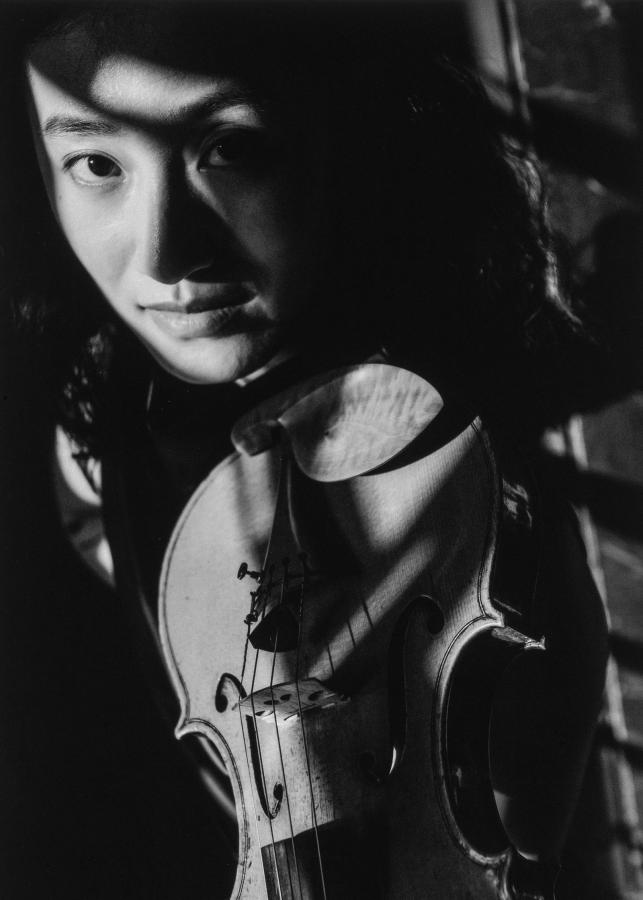 Ein Aktenkoffer steht zwischen den Füßen eines schick gekleideten Mannes in einer U-Bahn.