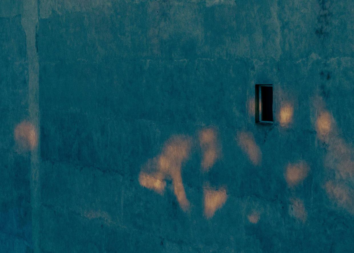 Ein Mann kehrt die Straße vor verhangenen Schaufenstern.