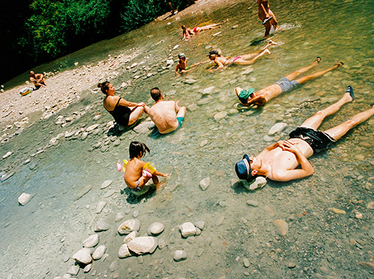 Menschen entspannen und baden in einem flachen Fluss mit Steinen.