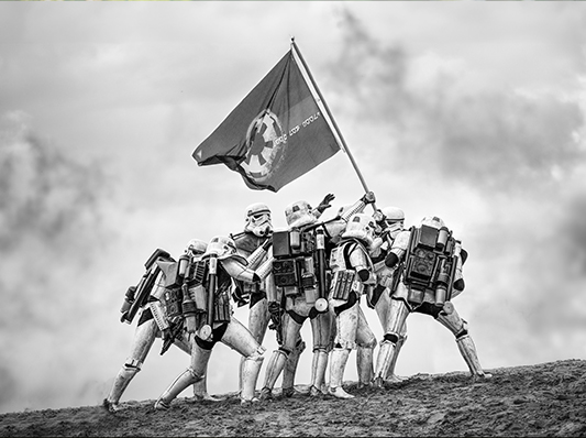 Eine Gruppe von Personen in Stormtrooper-Kostümen, die eine Flagge auf einem Hügel hissen.