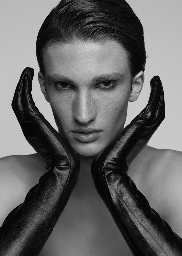 Ein Schwarz-Weiß-Porträt eines Mannes mit Handschuhen vor dem Gesicht.