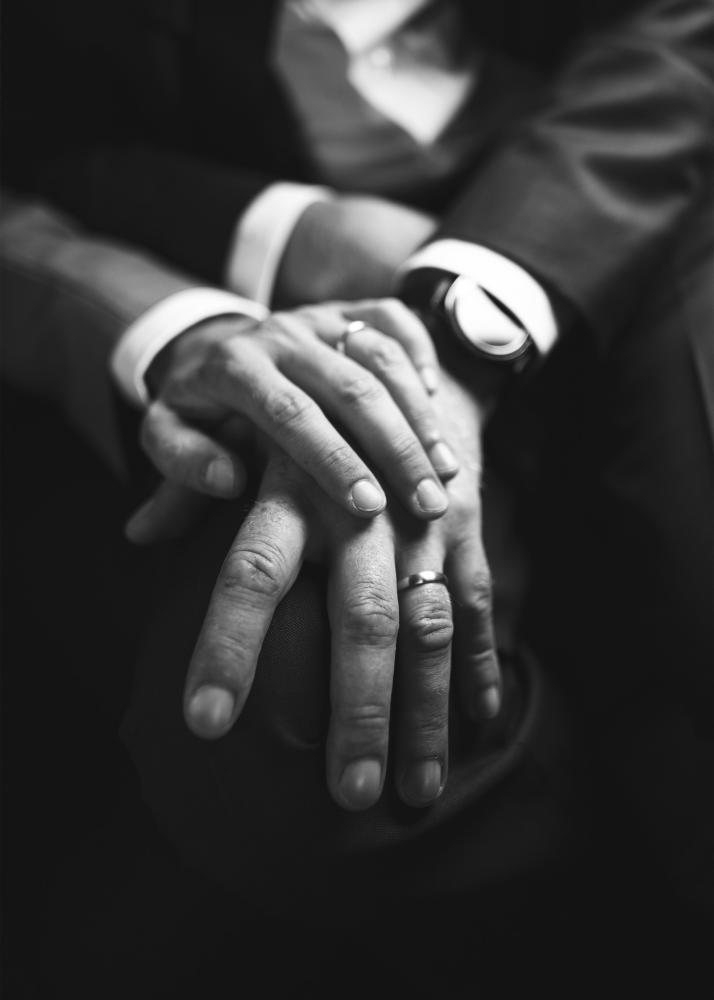 Zwei Hände mit Ringen, die sich in einer intimen Geste berühren.