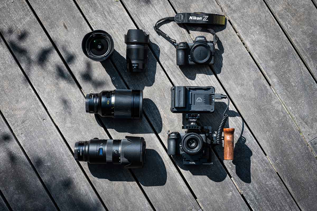 Eine Sammlung von Kameras und Objektiven liegt auf einem Holzboden.