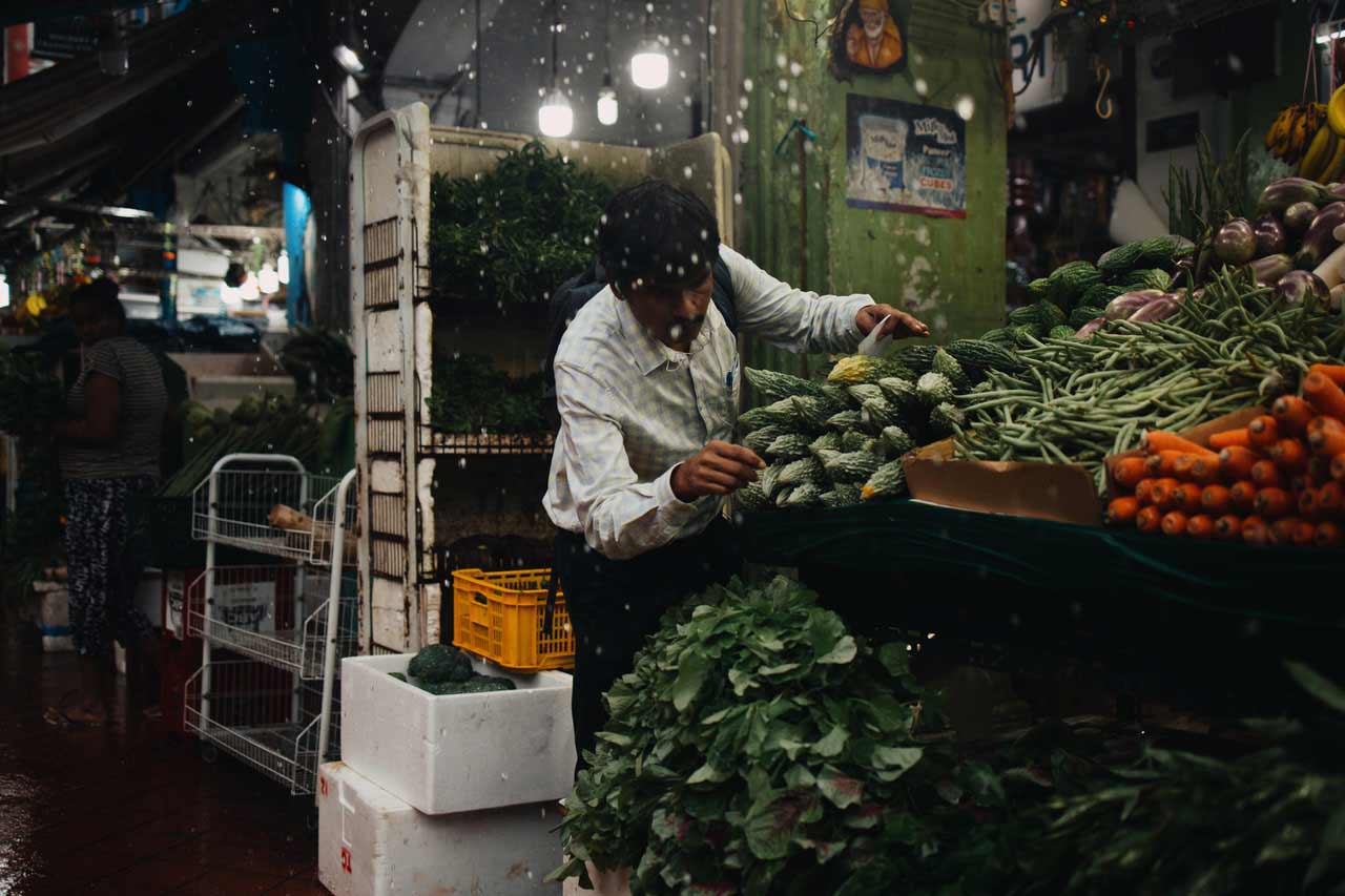 Ein Mann sucht sich auf einem Markt Früchte zum kaufen heraus.