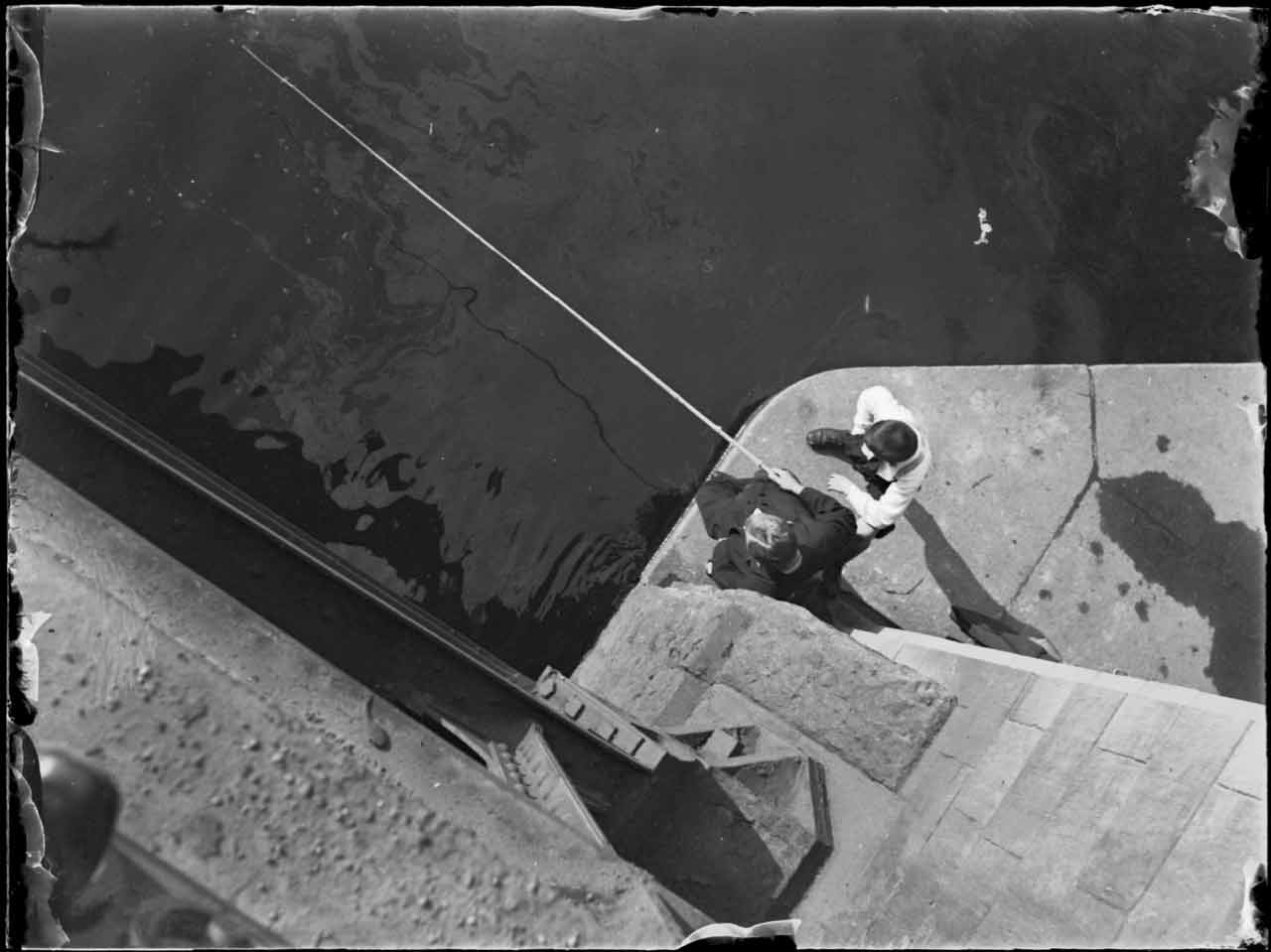 Zwei Angler in einem Hafen von oben herab fotografiert.