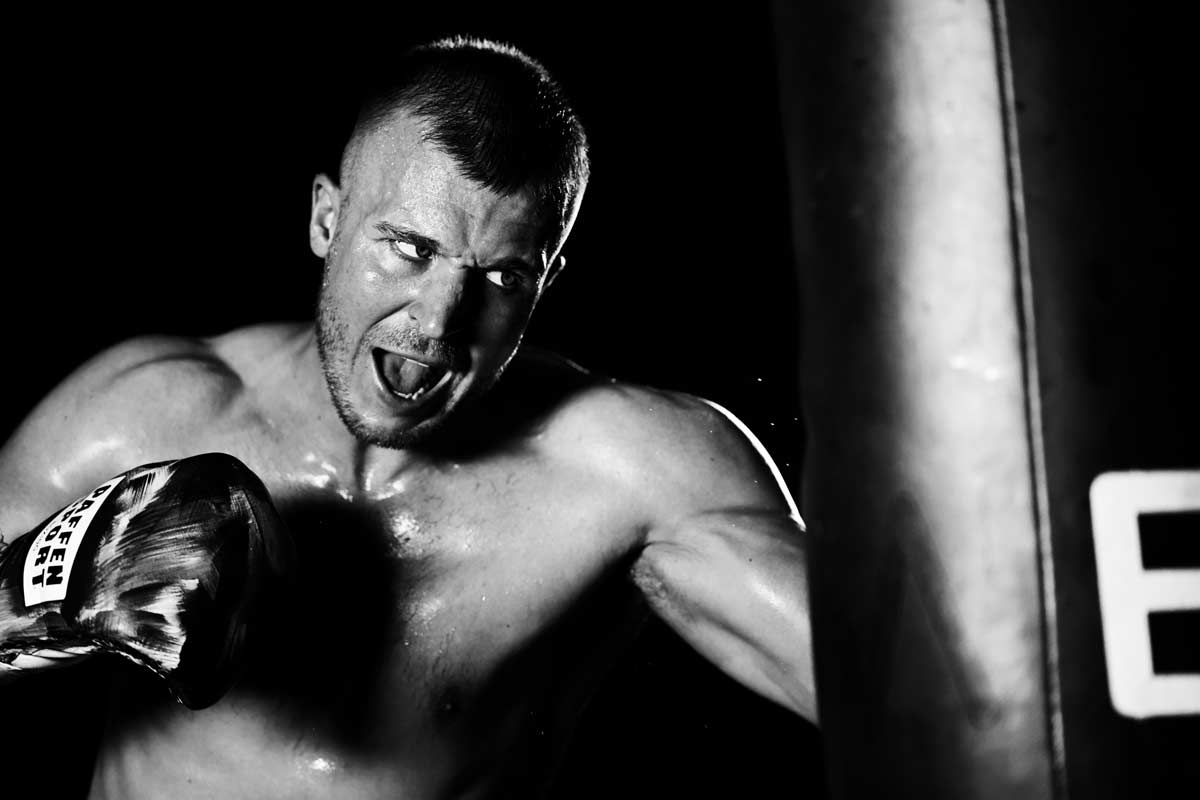 Ein Boxer trainiert mit angestrengtem Blick an einem Boxsack.