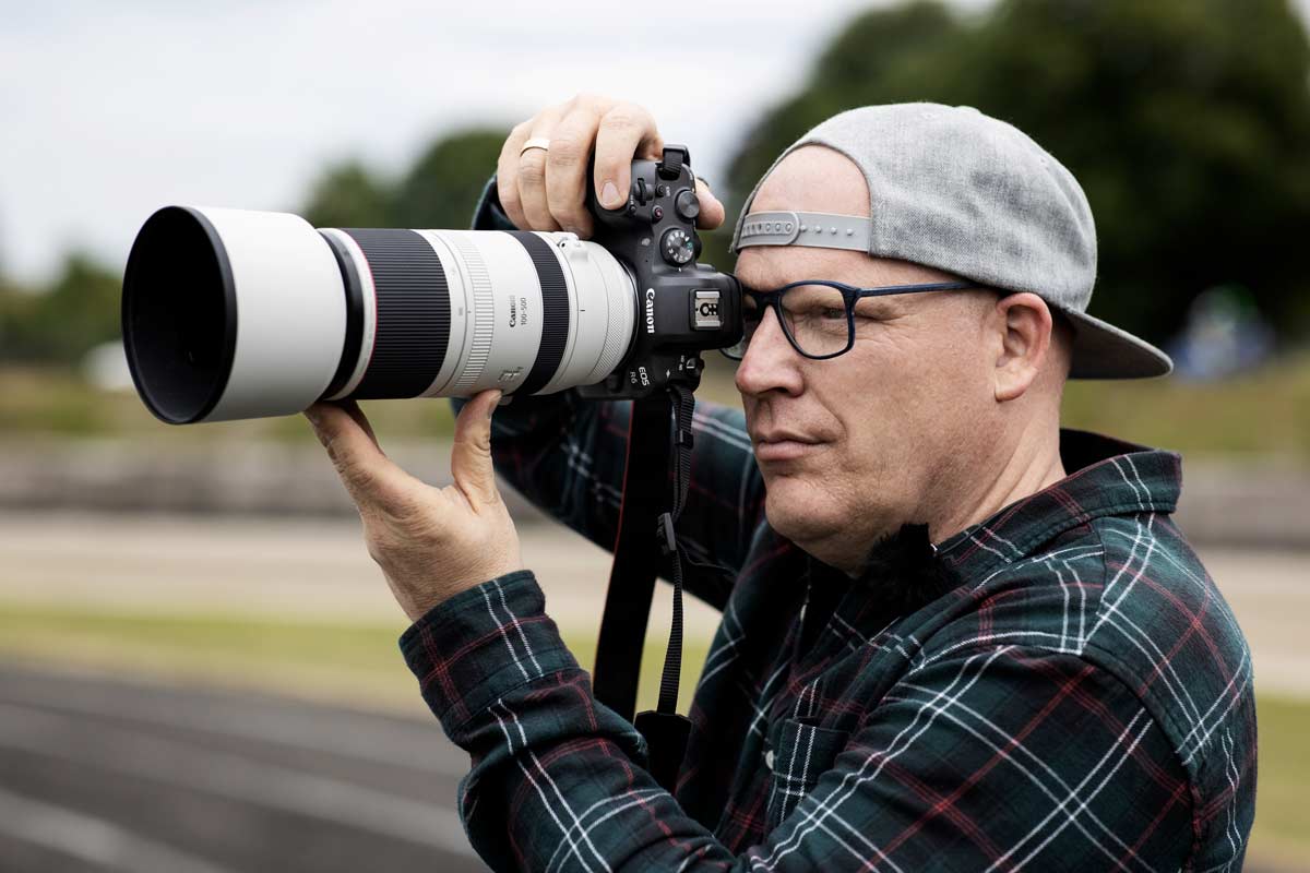 Ein Fotograf blickt konzentriert durch seine Canon-Kamera.