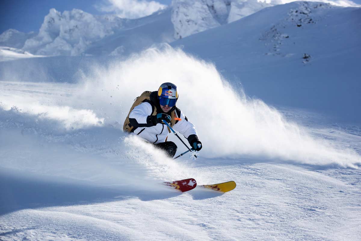 Ein Skifahrer fährt mit großem Schneewirbel einen Hang hinab.